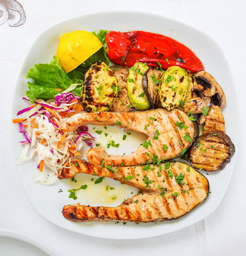 Sliced swordfish grilled with grilled vegetables like eggplant, zucchini and pepper, sprinkled with chopped parsley leaves. Top view.