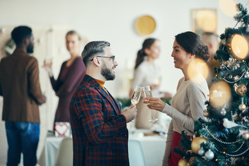 Side view portrait of modern adult couple talking and drinking champagne during Christmas banquet, copy space