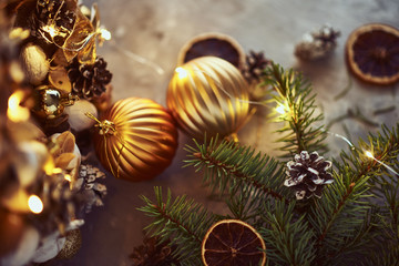 Obraz na płótnie Canvas Christmas decorations with golden balls, fir tree branch and garland lights on a dark background