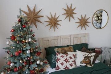 cozy bedroom with a Christmas tree decorated for the new year in red-green tones