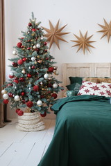 cozy bedroom with a Christmas tree decorated for the new year in red-green tones