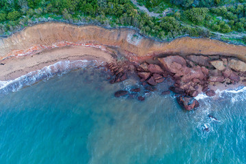 Looking down at large rocks and boulders on ocean beach - aerial view