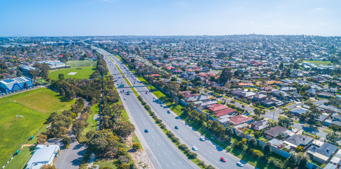 Fototapeta premium Cars driving on Monash freeway through Wheelers Hill suburb in Melbourne, Australia on sunny day - aerial panorama