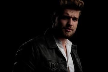 man wearing leather jacket standing aside and looking the other