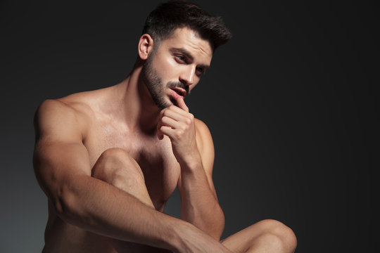 young naked fashion model looking to side and touching lips