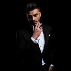 businessman wearing black suit standing and touching chin pensive
