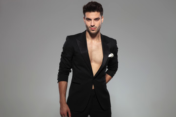 fashion man standing and hiding a present behind him happy