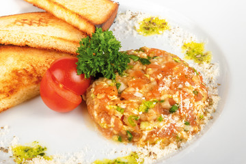 Beef steak tartare with croutons. raw beef with onions on the white plate decorated with cherry tomato. close up view