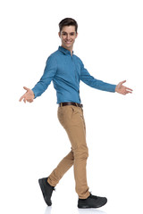 side view of happy young man walking and opening arms