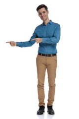 happy young man in blue shirt pointing finger to side