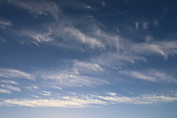 Cirrus clouds scattered across a bright blue sky