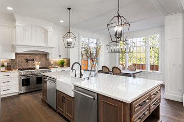 Beautiful kitchen in new traditional style luxury home, with quartz counters, hardwood floors, and...