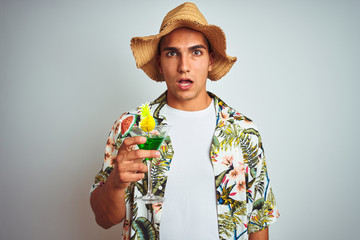 Young handsome man drinking cocktail on holiday over white isolated background scared in shock with...