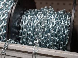 Roll of steel chain sitting in indoors storage area rolled up and spooled
