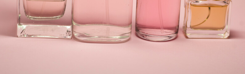 Woman, beauty and cosmetics concept: a bottles with liquid perfume at pink background