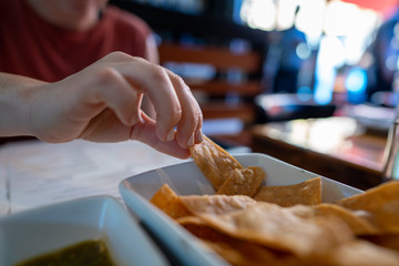 Woman hand grabbing gourmet tortilla at table of Mexican restaurant