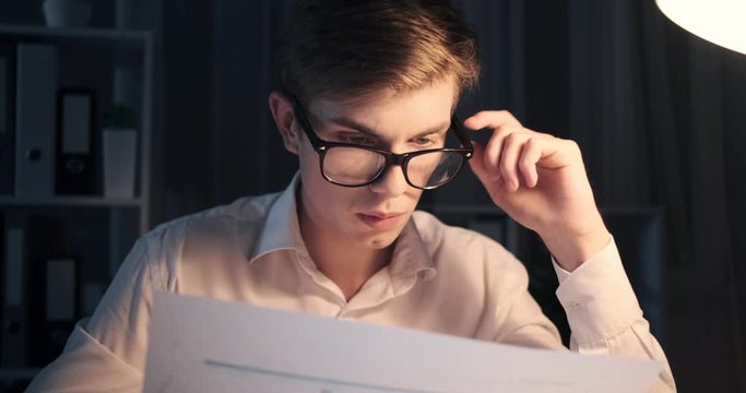 Tired businessman analyzing document late night at office