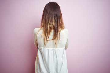 Young beautiful woman standing over pink isolated background standing backwards looking away with crossed arms