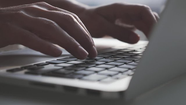 Close up fingers typing on laptop computer keyboard in office. Businessman or businesswoman hands typing on keyboard.