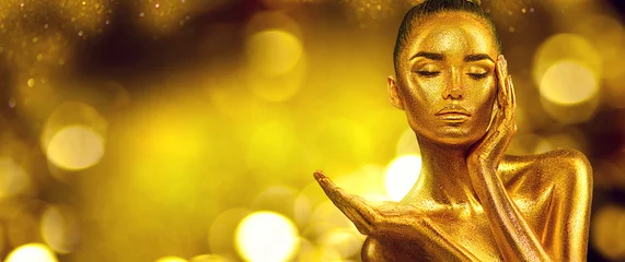 Goldene Frauenhaut. Weihnachtsschönheitsmode-Modellmädchen mit goldenem Make-up, Haar und Schmuck auf Goldhintergrund. Hand zeigen, Produkte vorschlagen, Verkäufe. Metallischer Glanz Modekunstporträt, Glamour © Subbotina Anna