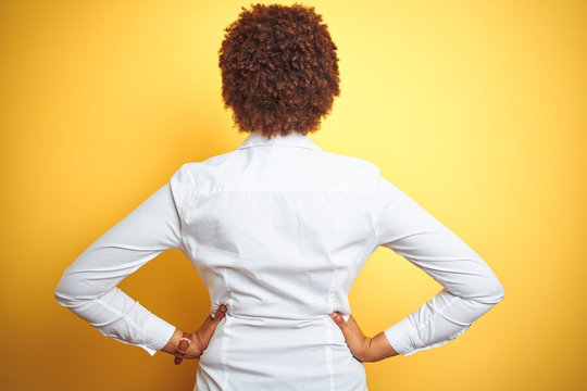 African american business woman over isolated yellow background standing backwards looking away with arms on body