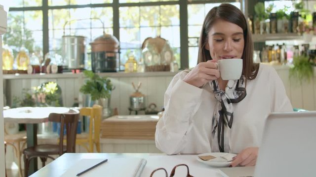 Beautiful smling cacausain brunette sitting in cafe and drinking coffee,
