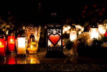 Candle snitch on the tombstone, All Saints' Day, the feast of the dead by night. Colorful bokeh background. Copy space