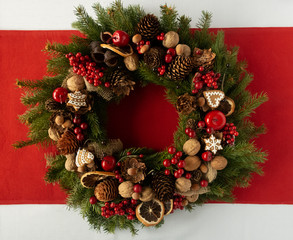 Christmas decorative wreath of spruce braches with dried oranges, candles, cones, gingerbreads. Concept of Christmas preparation, atmosphere. Wishes card. Hand made wreath. Flat lay