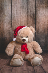 Teddy bear in winter clothing, dressed as Santa isolated on wooden