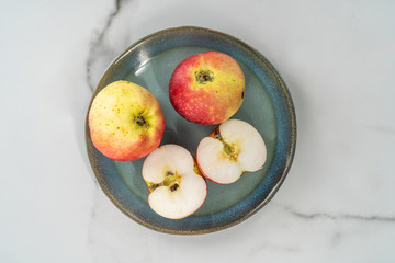 Pieces of apple served on a blue plate on a marble background. A fresh, healthy, snack.