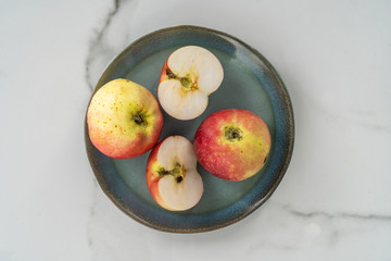 Pieces of apple served on a blue plate on a marble background. A fresh, healthy, snack.