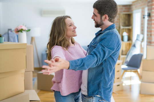 Young couple dancing celebrating moving to new apartment around cardboard boxes