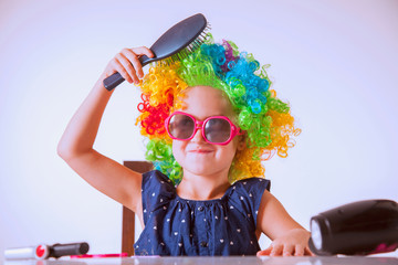 Portrait of young beautiful girl in colorful wig making herself hairstyle