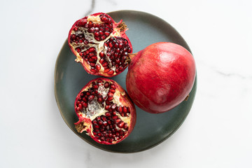 The cut pomegranate lies on a blue dye. Close-up of the center of a pomegranate. An ingredient of exotic juice. Pomegranate particles on a marble background.