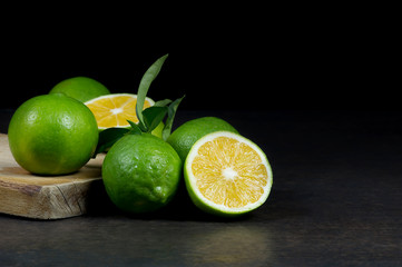 Fototapeta na wymiar fresh ripe organic green lemons on black rustic background, lime citrus healthy fruit concept