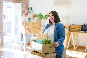 Young couple moving to new apartment, beautiful woman moving cardboard boxes and smiling happy