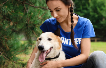 Female volunteer with homeless dog at animal shelter outdoors