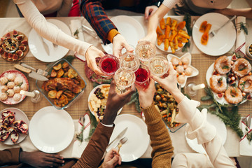 Top view background of people raising glasses over festive dinner table while celebrating Christmas with friends and family, copy space - obrazy, fototapety, plakaty