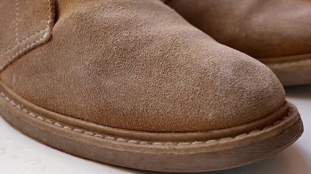 water drops fall on waterproof suede leather desert boots and roll off from surface. extreme closeup 4k UHD video footage