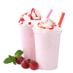 Tasty fresh milk shakes in plastic cups with ingredients on white background