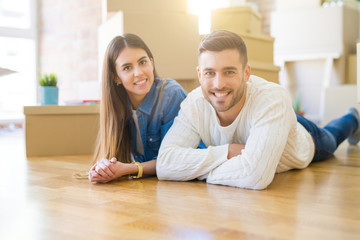 Young beautiful couple lying on the floor of new house, smiling in love very happy for moving to new apartment