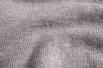 Grey knitted sweater as background, closeup view