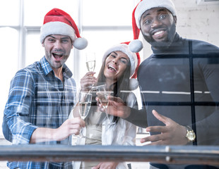 Merry Christmas and Happy New Year 2020. Multiracial young creative people are celebrating holiday in modern office.Group of young business people are drinking champagne and having fun in coworking.