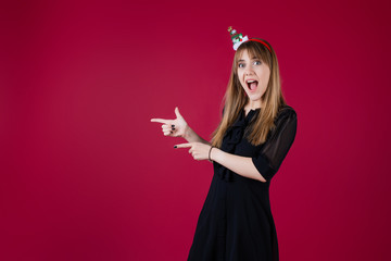woman wearing funny christmas hoop pointing at copyspace isolated over red