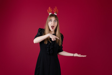 woman wearing funny christmas hoop with copy space on her hand isolated over red