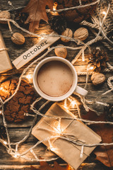 Cup of cocoa, garland, cookies, nuts, dried autumn leaves on  wood background. Autumn composition.