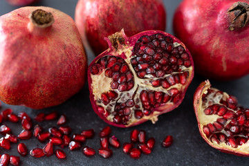 Different parts of the pomegranate fruit lie on the kitchen counter. Pomegranate on a black background.