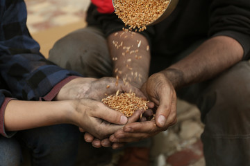 Poor homeless people taking wheat from donator outdoors, closeup