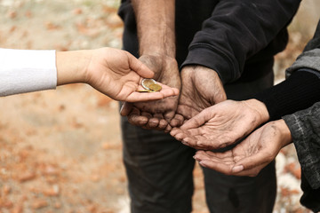 Woman giving poor homeless people money outdoors, closeup