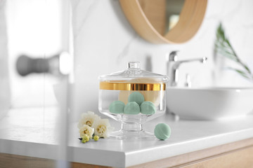 Jar with bath bombs and bath sponge on white countertop indoors